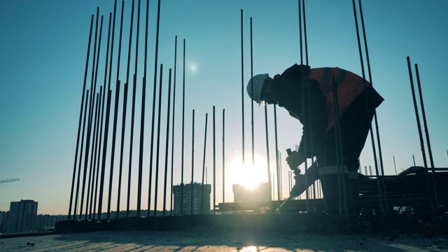 男工程师在未完工的建筑中钻地板。视频素材