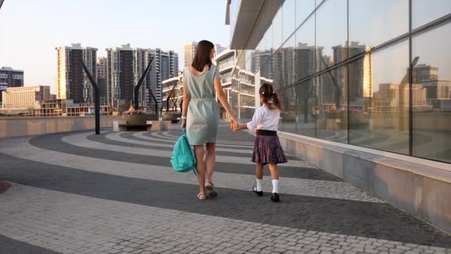 年轻的母亲带着穿着制服的小女儿早上去上学视频素材