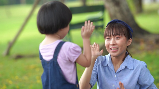 妈妈和女儿在院子里一起玩石头剪刀布游戏视频素材