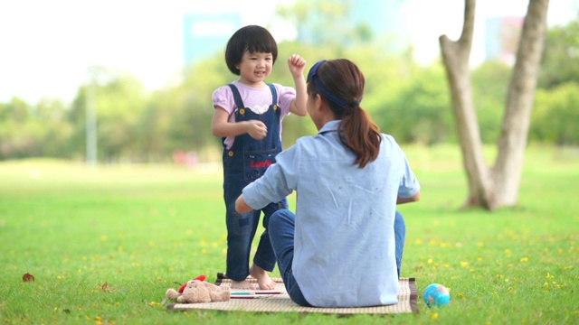 妈妈和女儿在院子里一起玩石头剪刀布游戏视频素材