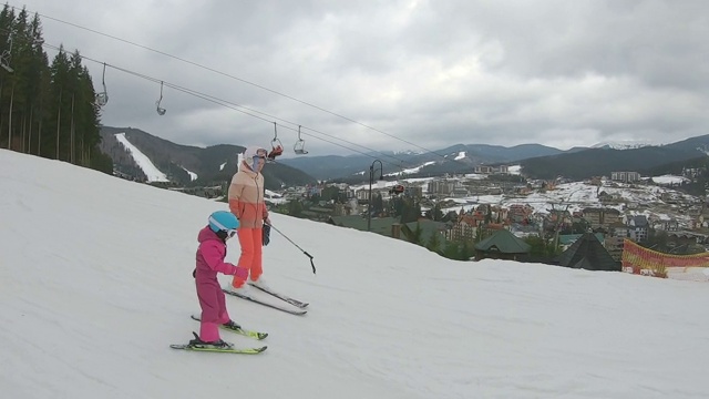 那孩子正和他母亲一起滑雪。视频素材