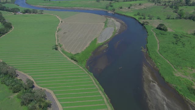 河流的鸟瞰图通过农村景观与农作物和起伏的山在Tarcoles，哥斯达黎加。视频素材