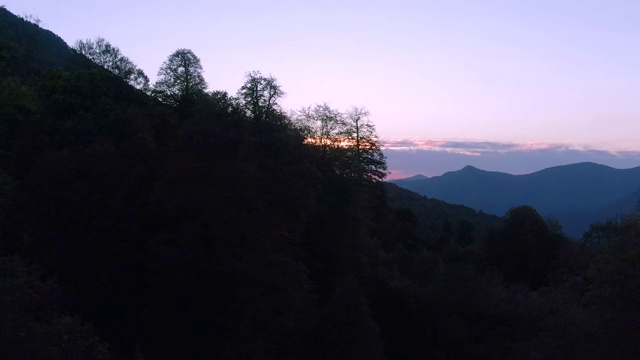 鸟瞰图飞行越过山脉，朝着一个彩色的魔术日落。秋天日落时的群山全景。在山里旅游和娱乐视频素材