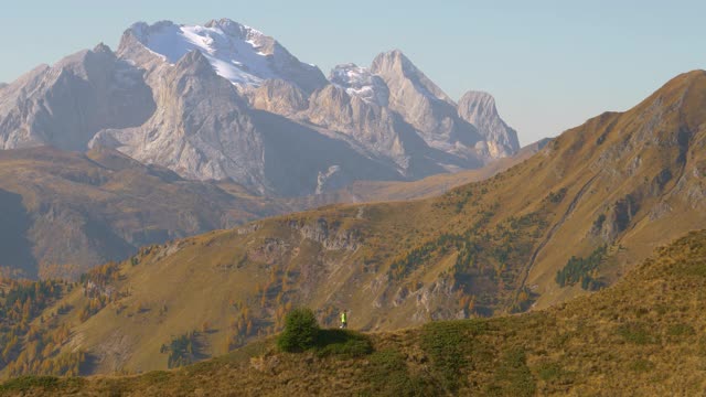 Dolomites的一个女人在爬下长满草的山的风景视频素材