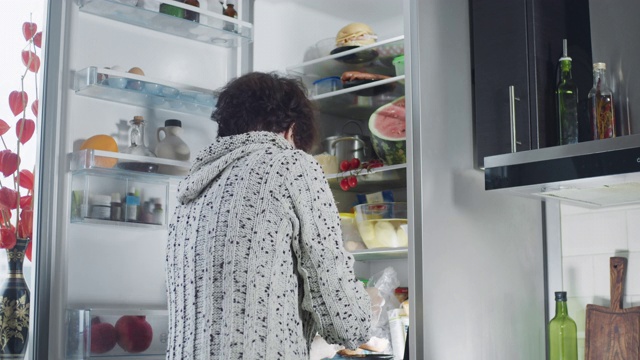 成熟的女人从冰箱里拿食物视频素材