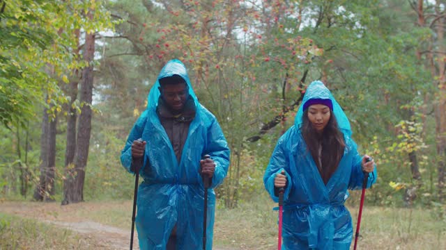 一对穿着雨衣在森林里徒步旅行的游客视频素材