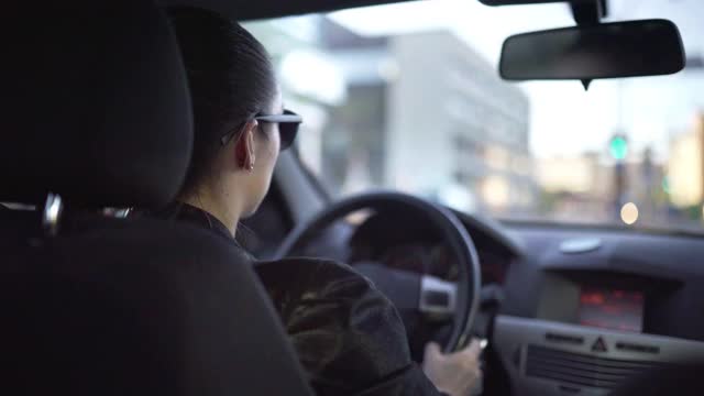 女人在拥挤的城市街道上开快车。公路旅行，超速，逃跑或追逐的概念。通勤者、女出租车司机或拼车者。驾驶舱的内部后视图。视频下载