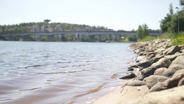 在芬兰的Jyvaskyla，海浪撞击岩石。湖和库奥卡拉桥。美丽的大自然芬兰。斯堪的纳维亚阳光明媚的夏季景观和城市景观。视频下载