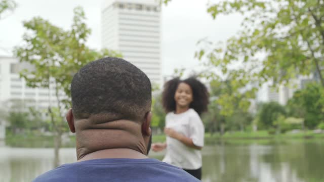 幸福多情的混血家庭的慢镜头。可爱的小女孩拥抱她的父亲在公园露齿微笑。爸爸带着小女儿一起享受夏天户外周末假期的时光。视频素材