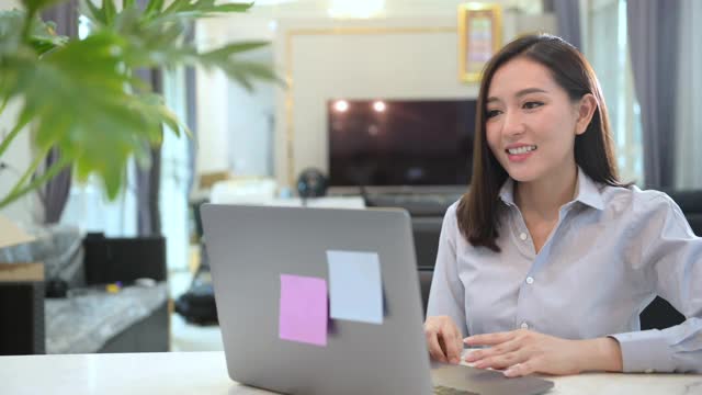 一位年轻漂亮的女商人正在家中通过电脑进行视频电话会议，商业技术概念。视频素材