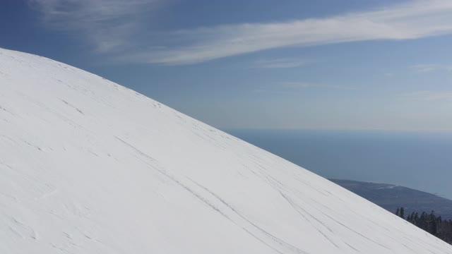 在阳光明媚的冬日里，从无人机上观看滑雪板下山视频素材