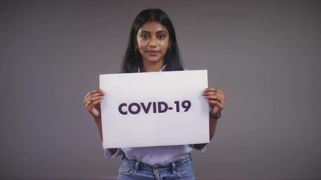 年轻的亚洲女人撕开Covid - 19标志肖像视频素材