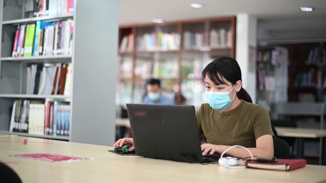 在图书馆学习的亚洲大学生观察社会距离视频素材