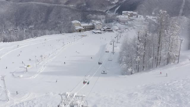 在山区度假胜地骑滑雪和滑雪板的人。鸟瞰图视频素材