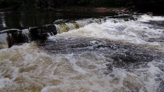 河谷中河床上的小瀑布和急流。气泡和白色的水产生漩涡视频素材