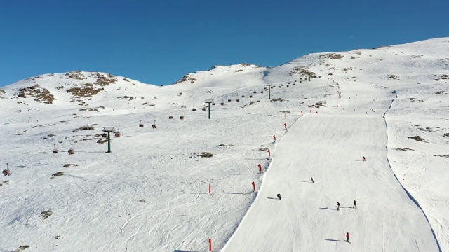 无人机镜头在冬季滑雪阳光明媚的日子里飞行-滑雪区Alpe Lusia，意大利白云石。有滑雪者和升降机的滑雪场视频素材