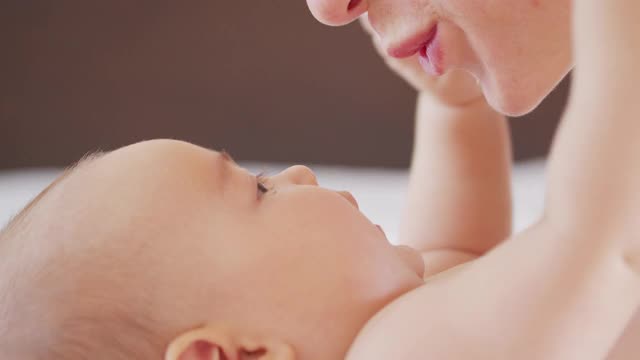 这是一位年轻的母亲和她刚出生的宝宝在婴儿房玩耍的特写镜头。孩子、婴儿、亲子、童年、生命、母亲的概念。视频素材