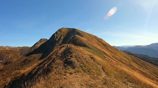 五彩斑斓的山景在秋天是金色的。美丽的秋景森林在群山中映衬着明亮的蓝天视频素材