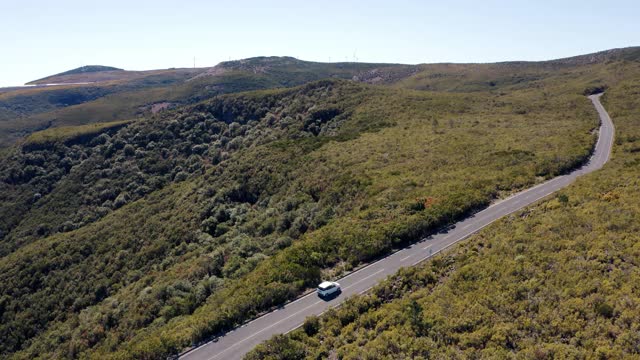 4K无人机拍摄的白色家庭汽车在空旷的道路上穿过荒野视频素材