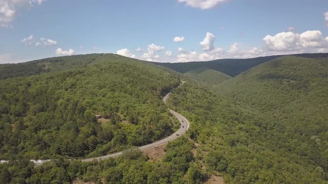 鸟瞰图蜿蜒的道路与割草汽车和卡车在高山口槽密林。视频素材