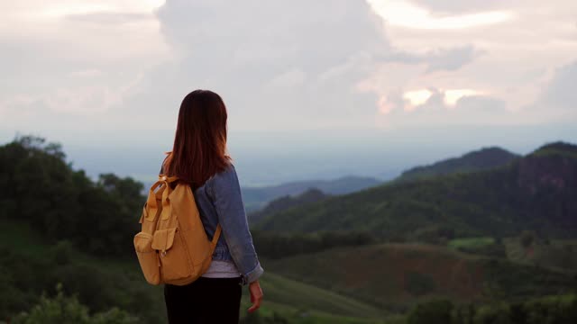 快乐的年轻女子旅行者放松和看美丽的日落在山顶视频素材