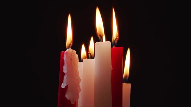 在黑色背景上燃烧着白色和红色的蜡烛视频素材