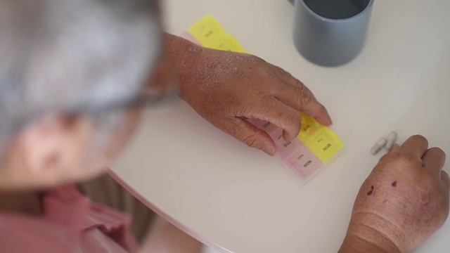 亚裔华人老人正在把药品放在药片收纳器里视频素材