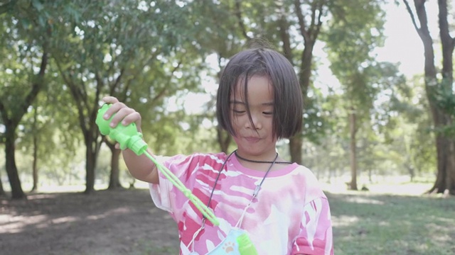 近亚洲短发可爱的女孩玩吹泡泡快乐的公园。夏天快乐的女孩。视频素材