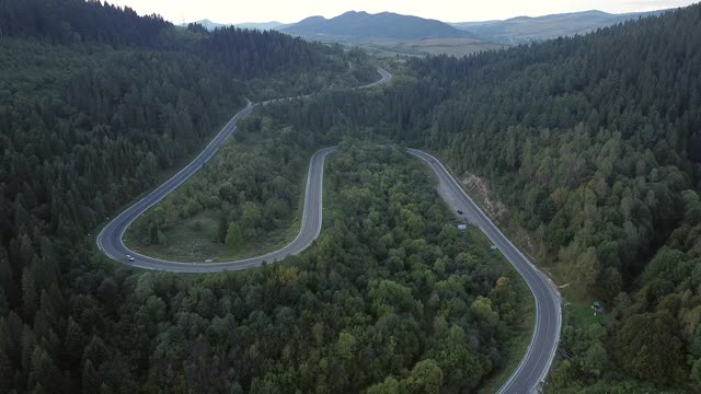 镜头B:无人机在蜿蜒曲折的道路上空盘旋。一辆汽车在蜿蜒的道路上行驶。无人机视频4 k。在夏天阳光明媚的日子里，山路蜿蜒在山上。迂回的视频素材