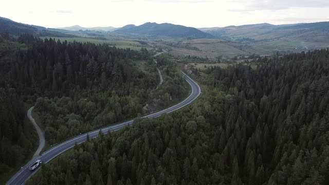 镜头B:无人机在蜿蜒曲折的道路上空盘旋。一辆汽车在蜿蜒的道路上行驶。无人机视频4 k。在夏天阳光明媚的日子里，山路蜿蜒在山上。迂回的视频素材