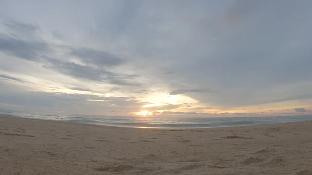 平静的海浪拍打着夏天的海滩，金色的日落，蓝色的天空视频素材