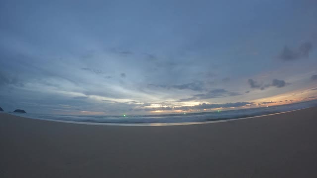 平静的海浪拍打着夏天的海滩，金色的日落，蓝色的天空视频素材