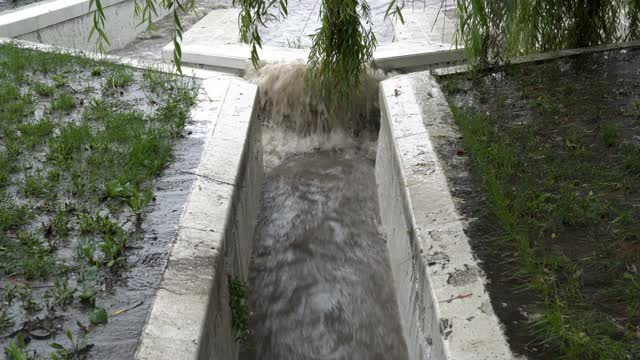 特写镜头显示，在大雨期间，一股湍急的脏水通过暴雨下水道的石头排水沟流入河中。坏天气。概念。4 k。视频素材