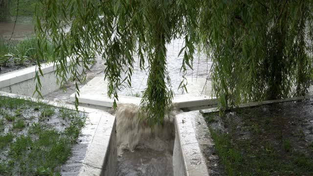 下大雨时，一股湍急的浑水通过雨下水道的石头排水沟流入河中。坏天气。概念。4 k。视频素材