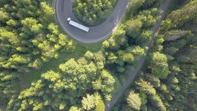 鸟瞰图蜿蜒的道路与割草汽车和卡车在高山口槽密林。视频素材