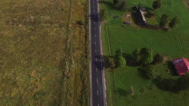 空中飞过蜿蜒的高速公路，在茂密的绿树丛中，日出时阳光穿透云层视频素材