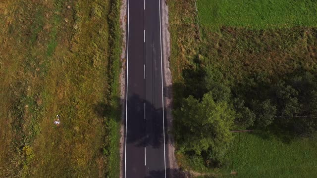 空中飞过蜿蜒的高速公路，在茂密的绿树丛中，日出时阳光穿透云层视频素材