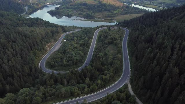 镜头B:无人机在蜿蜒曲折的道路上空盘旋。一辆汽车在蜿蜒的道路上行驶。无人机视频4 k。在夏天阳光明媚的日子里，山路蜿蜒在山上。迂回的视频素材