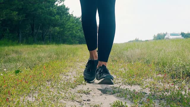 低角度拍摄，慢动作:一个年轻的女孩在早晨进行体育运动，沿着松树林跑步视频素材