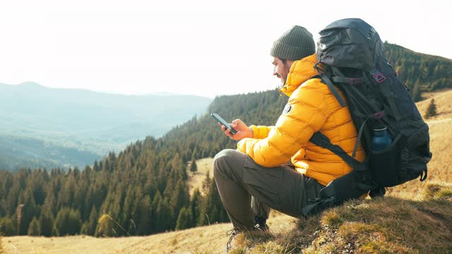 一个年轻人在徒步旅行时使用手机。视频素材