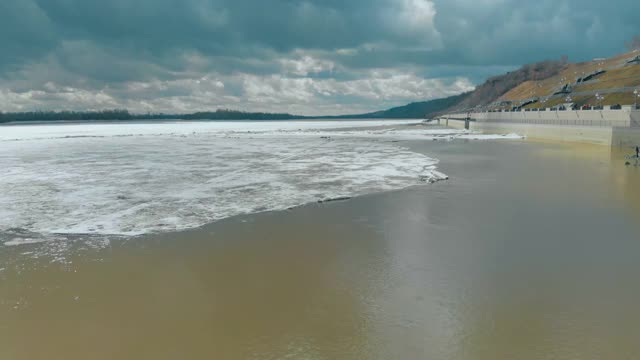 深深的半冻的河流，堤岸上灰色的建筑视频素材