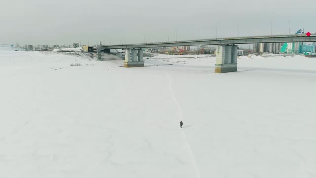 一个人的剪影走在结冰的河上的雪道上视频素材