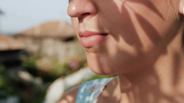 女人在喝酒。侧面的女性手拿酒杯与红酒到他们的嘴，喝它在阳光明媚的日子在大自然。特写镜头视频素材