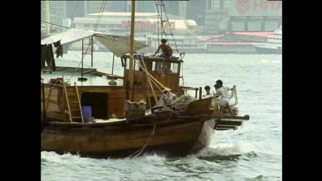 在香港港口内，渔民在移动船只上整理渔网;1989视频素材