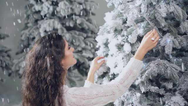 有圣诞树的漂亮女孩。年轻女子摸着圣诞树。冬天假日的庆祝活动视频素材