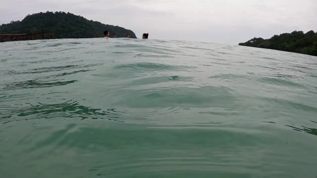 一群亚洲游客在海里玩。在热带岛屿上，小雨滴入平静的海水中。在海里聊天的女性朋友。视频素材