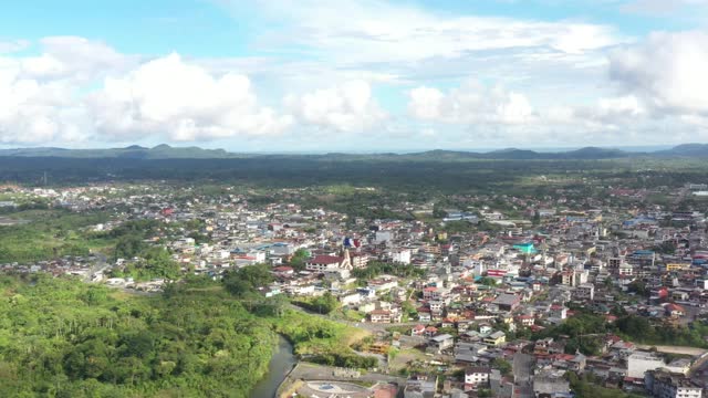 从高处俯瞰位于群山之中，被森林和小山丘包围的城市视频素材