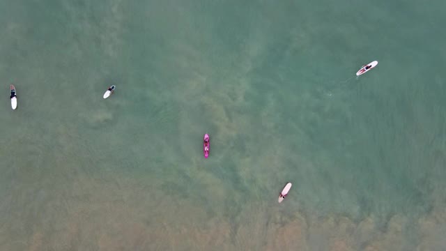 4k空中俯视图缩小冲浪板上的冲浪者准备赶上海浪的大海视频素材