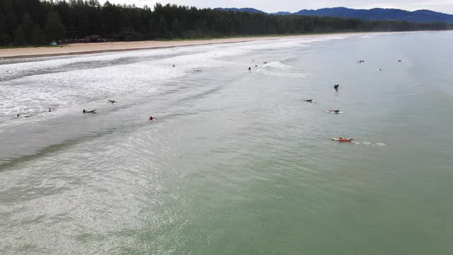 4k鸟瞰图通过多莉放大的海滩波浪和冲浪者在海里视频素材