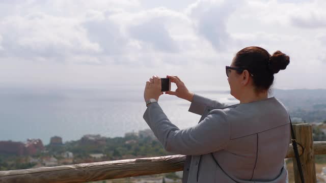 一个女人在西班牙的海岸拍照，4k慢镜头60fps视频素材